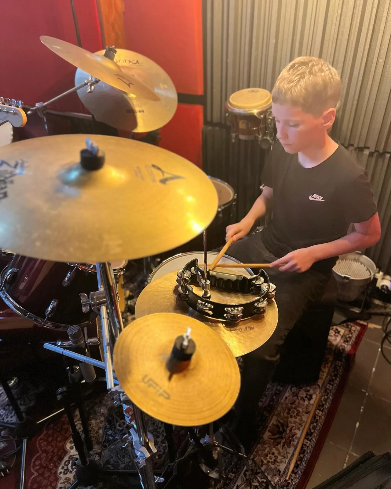 Een deelnemer zit achter een drumstel en houdt drumstokken vast.