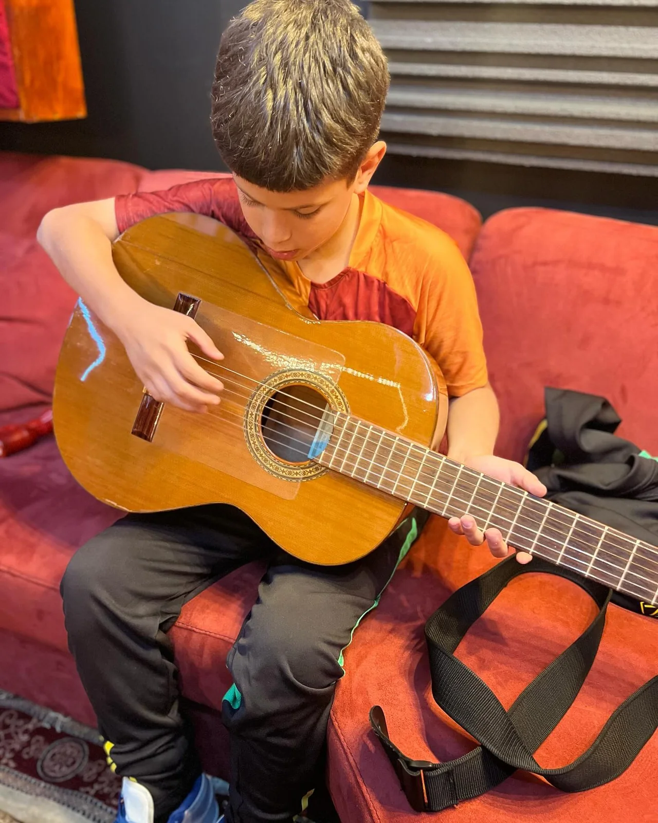 Een deelnemer zit op een bank en bespeelt een akoestische gitaar.