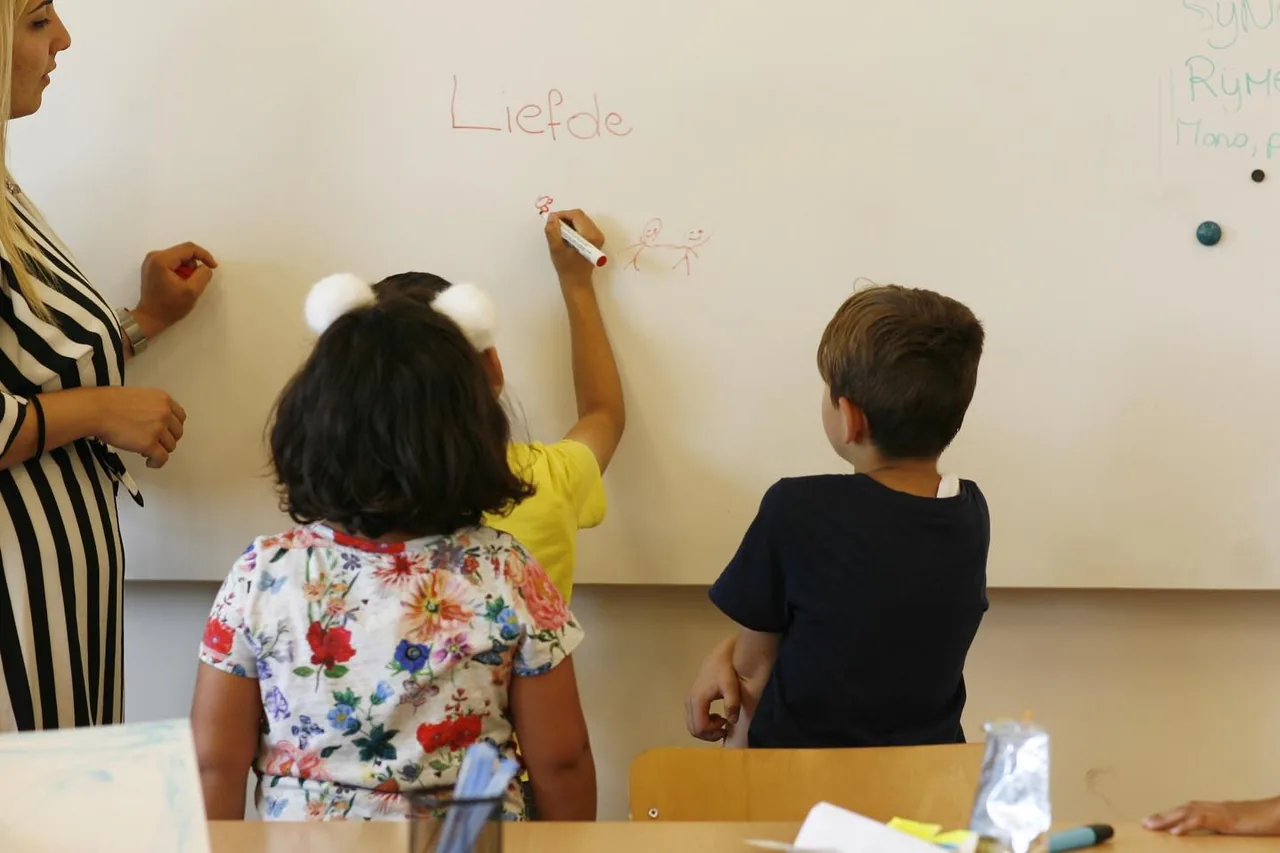 Kinderen tekenen op een whiteboard, naast een begeleider.